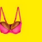 Two coconuts in bright pink bra on yellow background. Woman breast metaphor. Plastic surgery,